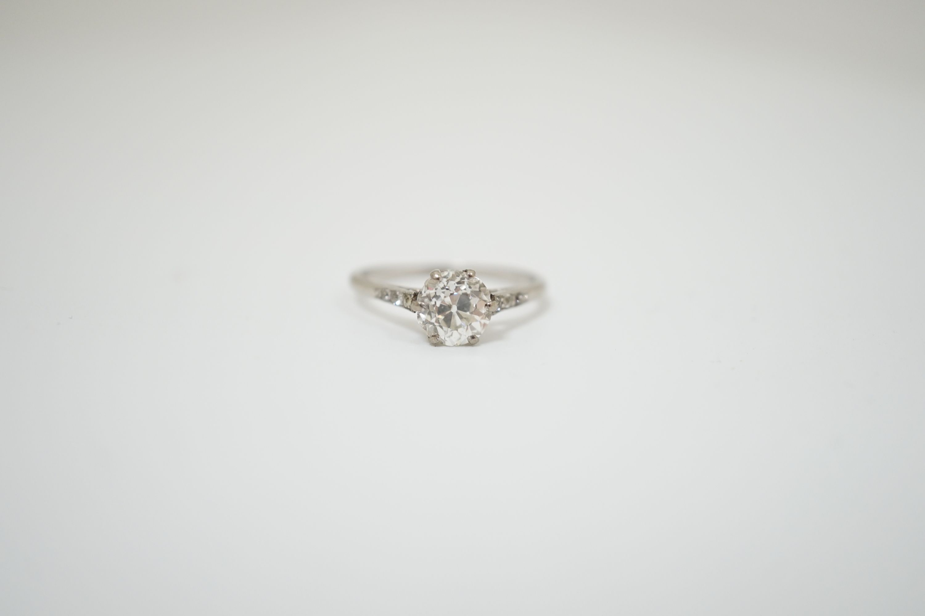 A platinum and single stone diamond ring, with diamond chip set shoulders